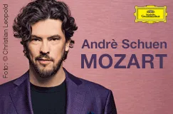 Andrè Schuen, MOZART, Mann mit Bart und dunklem Haar vor rosa Hintergrund, gelbes Logo oben rechts.