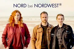 "NORD bei NORDWEST" steht oben. Drei Personen stehen vor einem Strand: eine Frau mit roten Haaren, ein Mann, eine Polizistin.