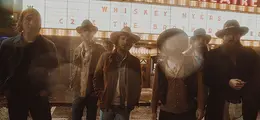 Auf einem Schild steht: "Whiskey Myers". Sechs Männer mit Hüten und Jacken stehen davor.