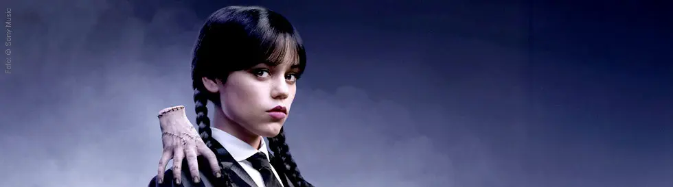 Eine junge Frau mit Zöpfen im Profil, ihre Schulter wird von einer entstellten Hand berührt.