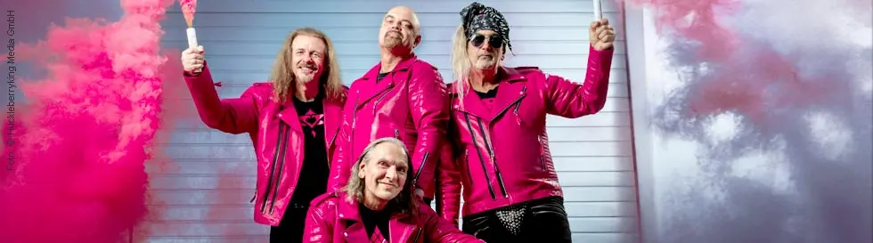 Vier Männer in pinken Lederjacken, zwei halten Rauchfackeln. Hintergrund in Grautönen. Alle tragen schwarze Shirts.