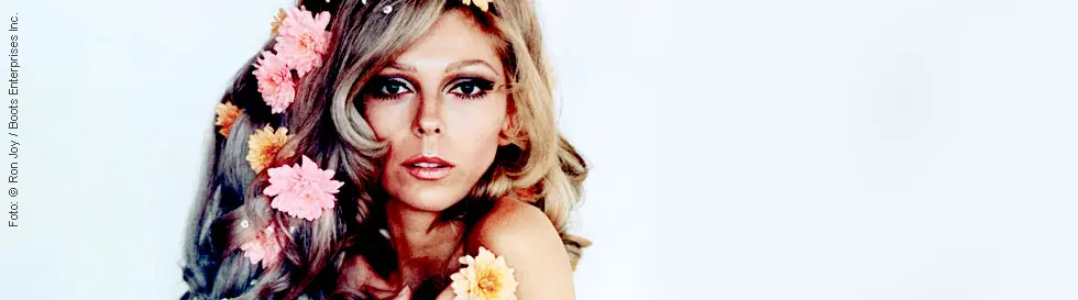 Frau mit Blumen im Haar, ausdrucksstarker Blick, pastellfarbene Ästhetik.