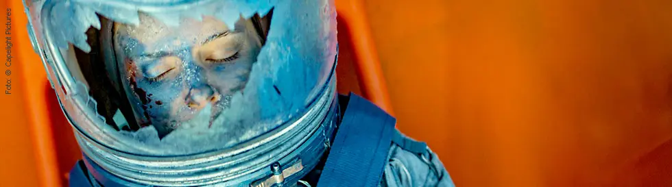 Frau mit geschlossenen Augen in einem Raumanzug mit zerbrochenem Helm. Hintergrund in orange Tönen.