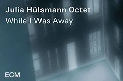 Text: "Julia Hülsmann Octet, While I Was Away, ECM." Ein verschwommener Blick in einen Innenhof bei Dämmerung.