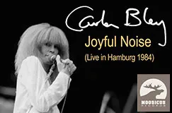 Text: "Carla Bley, Joyful Noise (Live in Hamburg 1984)". Schwarz-Weiß-Foto einer Person mit Mikrofon, Logo unten rechts.