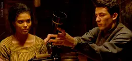 Eine Frau und ein Mann in historischer Kleidung betrachten eine Phonographenwalze mit Schalltrichter.