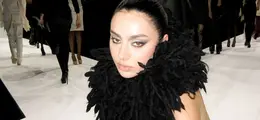 Eine Frau trägt ein schwarzes, flauschiges Outfit auf einem Laufsteg.