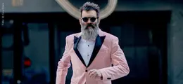 Ein Mann mit Bart in rosa Anzug und Sonnenbrille geht selbstbewusst nach vorne.