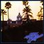 Der Text "Hotel California" in leuchtendem Blau, mit einem Gebäude und hohen Palmen im Hintergrund.