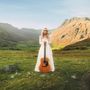Eine Frau in einem weißen Kleid hält eine Gitarre auf einer grünen Wiese in einer Berglandschaft., CD