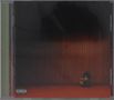 Unten links: "Parental Advisory Explicit Content". Person sitzt mit gesenktem Kopf in einem dunklen Raum auf rotem Boden.