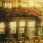 Text "BE LUCKY" über einer Ladenfassade mit Blumenranken. Vor dem Laden sitzt eine Person auf einer Bank., LP
