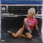 Der Text "FEMME FATALE" steht auf einer Schärpe. Eine Person sitzt vor einem Auto, trägt ein rosa T-Shirt und hat Tattoos., 2 LPs