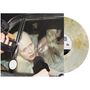 Eine Person mit blonden Haaren sitzt in einem Auto, umgeben von Mikrofonen. Eine Schallplatte halbiert das Bild., LP