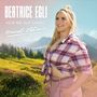 Beatrice Egli: Hör nie auf damit, Heimat Edition. Frau in kariertem Hemd auf Wiese, Berge im Hintergrund., 2 CDs