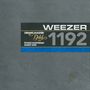 Texte: "Grand Master Gold", "Weezer", "1192", "Studio Mastering Audio Tape". Graue Oberfläche, schwarzes Rechteck, blaue Linie., LP