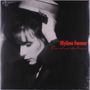Auf einer Aufnahme steht in roter Schrift "Mylène Farmer, Cendres de lune". Sie zeigt eine Frau in Schwarz-Weiß, die einen Hut anfasst., LP