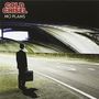 Text: "COLD CHISEL NO PLANS". Ein Mann im Anzug steht mit einem Koffer allein auf einer leeren, beleuchteten Straße.
