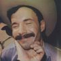 Ein Mann mit Schnurrbart und Cowboy-Hut lächelt, während jemand sein Gesicht sanft hält., LP