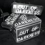 "OUT OF DARKNESS" steht auf mehreren gepackten Reiseboxen in einer Szene mit Stühlen im Hintergrund., CD