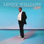 LENNY WILLIAMS, Changing. Eine Person in Anzug und Schal steht vor blauem Hintergrund, trägt weiße Schuhe.