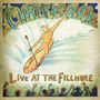 "Chris Isaak: Live at the Fillmore" in farbenfroher Schrift über einer surfenden Figur mit Mikrofon, umgeben von jubelndem Publikum., CD