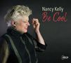 Text: "Nancy Kelly Be Cool." Porträt einer lächelnden Frau mit blondem Haar vor dunklem Hintergrund.