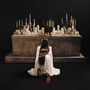 Rückenansicht einer Frau im weißen Kleid mit "ESTRUS" darauf, kniend vor einem Altar mit vielen Kerzen und einer schwarzen Katze., CD