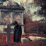 Ein Mann in einem dunklen Mantel steht nachdenklich vor einem alten Grabstein auf einem rot gefärbten Friedhof., CD