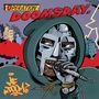 „OPERATION: DOOMSDAY.“ Ein Mann in einer Maske und Kapuze hält ein Mikrofon, hinter ihm rauchen Gebäude. Comicstil., MC