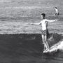 Zwei Jungen surfen auf kleinen Wellen. Einer steht auf dem Surfbrett, der andere sitzt im Hintergrund im Wasser., 2 LPs