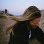 Langes, fließendes Haar weht im Wind über einem kargen, verschwommenen Landschaftshintergrund., LP