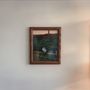Kein Text vorhanden. Ein gerahmtes Foto an der Wand zeigt eine Person, die auf einer grünen Wiese sitzt., CD