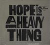 Text: "HOPE IS A HEAVY THING", kleinerer Text oben rechts: "The new record from JOY OLADOKUN". Schwarze Schrift auf grauem Hintergrund., CD