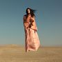 Keine Texte. Eine Frau in einem fließenden, pfirsichfarbenen Kleid steht in einer Wüstenlandschaft., LP