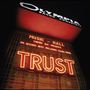 "OLYMPIA BRUNO COQUATRIX" und "TRUST" in leuchtenden Lettern eines Veranstaltungsortes bei Nacht., 2 CDs