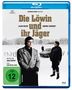 Der Text sagt: "Die Löwin und ihr Jäger". Zwei Personen stehen vor einem Auto im Schnee. FSK 12 Logo unten links.