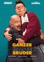 GANZER HALBER BRUDER. Zwei Männer umarmen sich, einer trägt eine rot-weiße Jacke und Kopfhörer um den Hals., DVD
