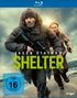 Text: "Jason Statham SHELTER", "FSK ab 16 freigegeben", "VORAB-COVER".  
Eine Person mit Mütze und Gewehr läuft am Strand, gefolgt von einer Frau., Blu-ray Disc