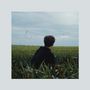 Keine Texte erkennbar. Eine Person im schwarzen Pullover sitzt vor einem Feld, im Hintergrund Windräder und bewölkter Himmel., CD
