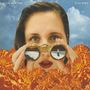 Text: "Alice Merton", "Visions". Eine Frau schaut durch ein Fernglas, umgeben von orangefarbenen Blumen, blauer Himmel., LP