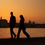 Keine sichtbaren Texte. Zwei Personen gehen am Wasser entlang, Silhouetten vor einem orangefarbenen Sonnenuntergang., CD