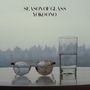 "Season of Glass" und "Yoko Ono" stehen oben. Eine Brille mit Rissen und ein halb volles Glas stehen vor einer Stadtkulisse., CD