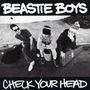 "BEASTIE BOYS" oben, "CHECK YOUR HEAD" unten. Schwarz-weiß Foto von drei sitzenden Personen auf Gehweg mit Instrumentenkoffern., CD
