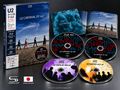 Text: "U2 CARNAVAL DE LUZ". Vier Männer gehen am Strand entlang, jeder im Anzug., 3 CDs und 1 Blu-ray Disc