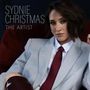 "Sydnie Christmas. The Artist." Eine Person in einem hellblauen Anzug mit roter Krawatte und dunklem Haar schaut ernst., CD