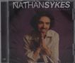 "NATHAN SYKES ULTRAVIOLET". Ein Mann lächelt und faltet die Hände, trägt ein helles Hemd vor dunklem Hintergrund., CD