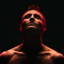 Dunkler Hintergrund, Oberkörper eines Mannes mit nach oben geneigtem Kopf, rot beleuchtet., CD