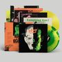 Stapel von Vinyl-Schallplatten und Hüllen mit Texten wie "DEVO", "NITE", "Laughing Gas!" in einem retro-futuristischen Stil., 2 LPs