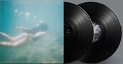 Keine Texte im Bild. Eine unter Wasser schwimmende Person neben zwei schwarzen Vinyl-Schallplatten.